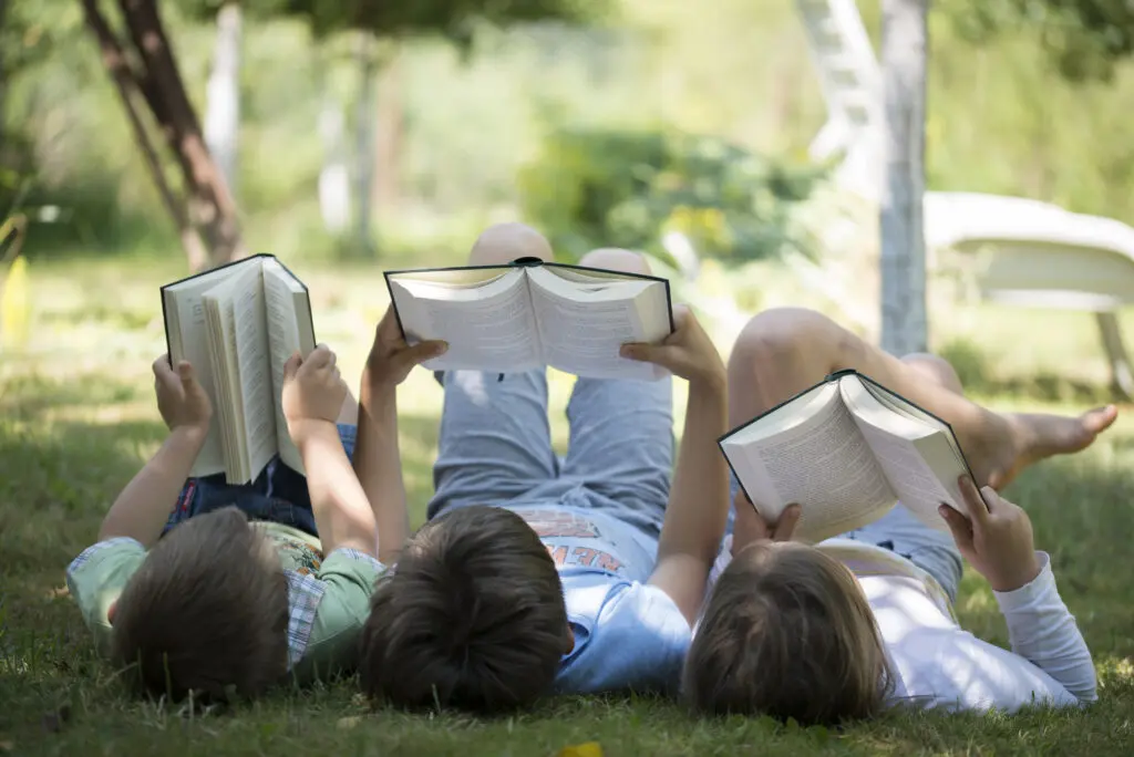 Enfant lisant allongés dans l'herbe