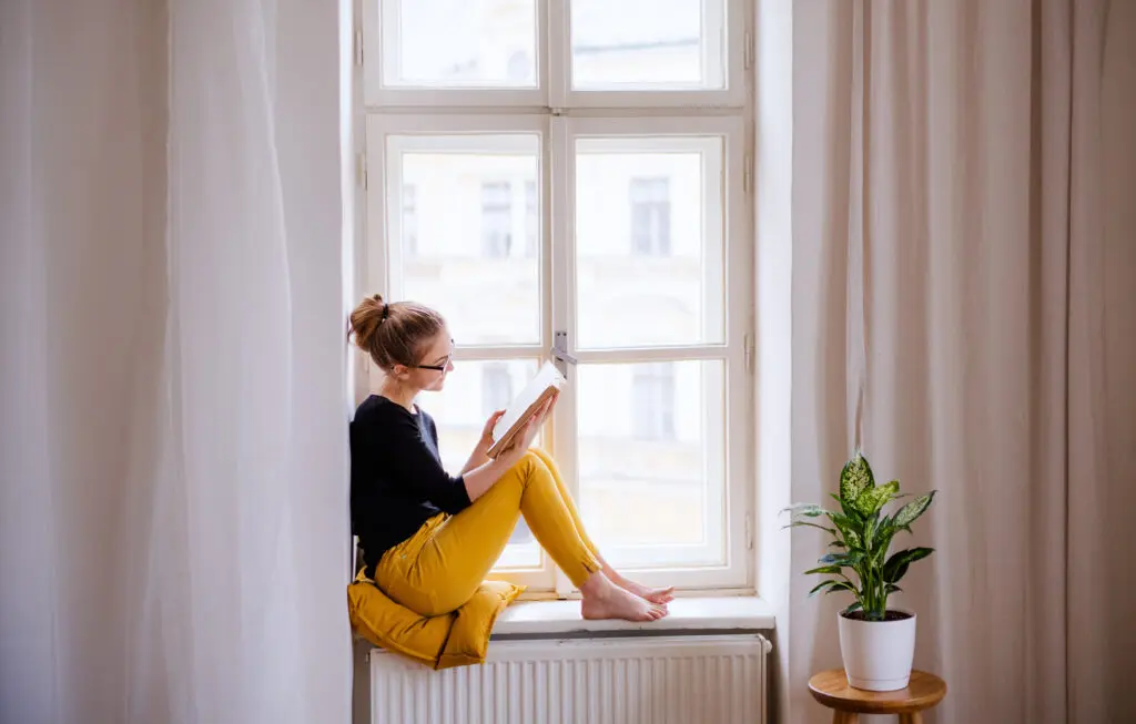 Jeune femme lisant au rebord de la fenêtre